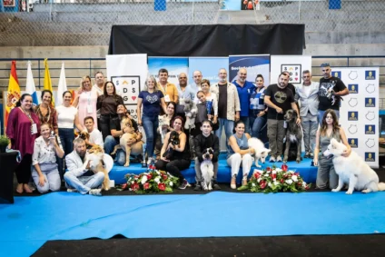 Group of people and dogs at a dog show event, with banners in Spanish.